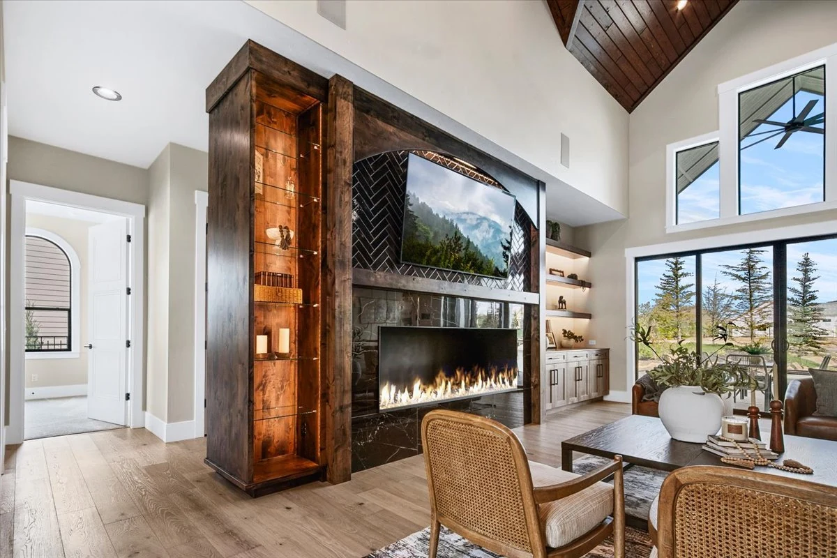 The Jane fireplace wall combining dark stone, timber display cabinets and metal details
