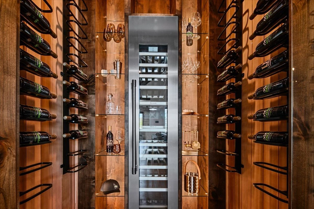 The Jane wine room with richly grained timber, black metal bottle racks and glass doors