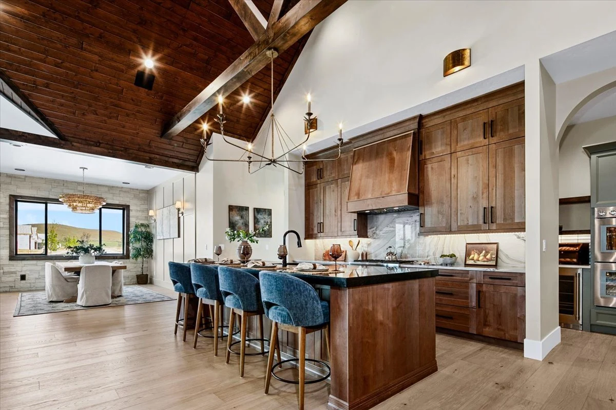 The Jane kitchen with a timber ceiling, oak cabinets, brass pendants and blue island seating