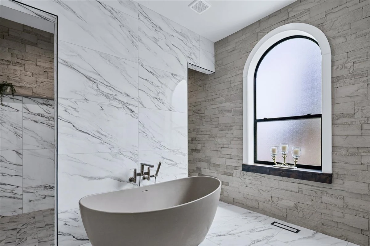 Freestanding bathtub beside an arched window