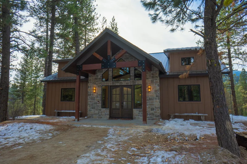 Close up of the front exterior of the Terrace Lakes Cabin by Bachman Custom Homes. Rich brown panel exterior with stone and warm toned wood details